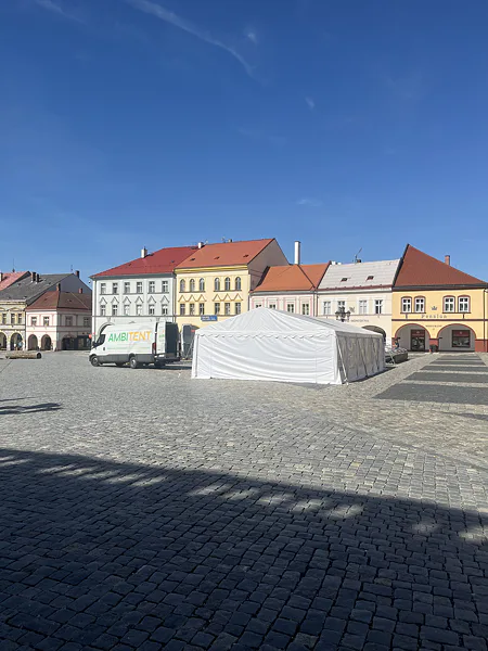 Rozestavěný bílý párty stan a dodávka Ambitent na náměstí v Jičíně.
