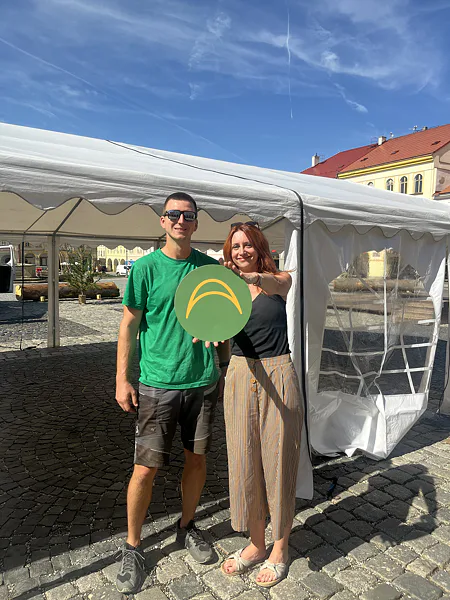 Dvojice s logem Ambitent před bílým párty stanem na festivalu v Jičíně.